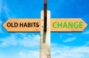 A sign pointing in two directions, to 'old habits' and to 'change'