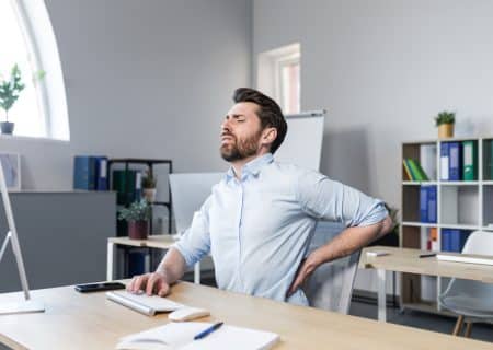 A businessman at work wearing a blue shirt with severe back pain.