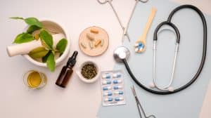 Several items related to holistic pain management, like herbs, vitamins, a stethoscope, and essential oils, on a blue and white background.